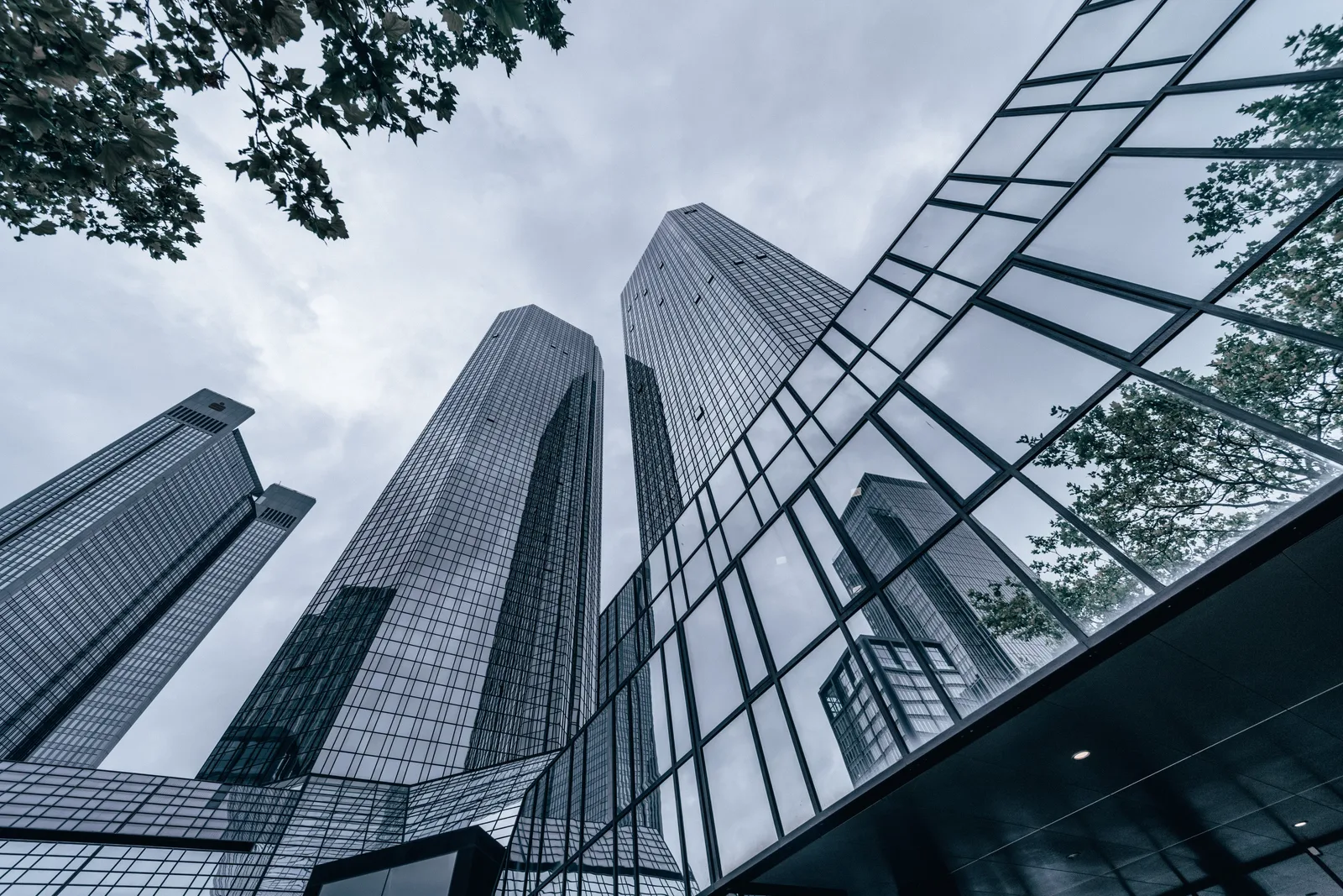 Modern skyscrapers with glass facades reflecting the urban skyline on an overcast day.