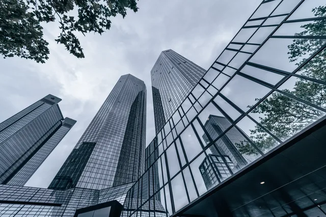 Modern skyscrapers with glass facades reflecting the urban skyline on an overcast day. Hitta företag i ett kontorskluster via adressregister