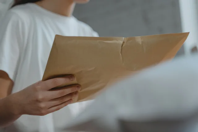 Close-up of a person holding a brown paper envelope, highlighting courier services or postal delivery indoors. Så ändrar företag sin registrerade adress hos Bolagsverket